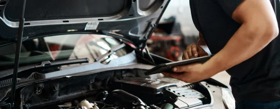 Mekaniker arbetar under motorhuven på en bil
